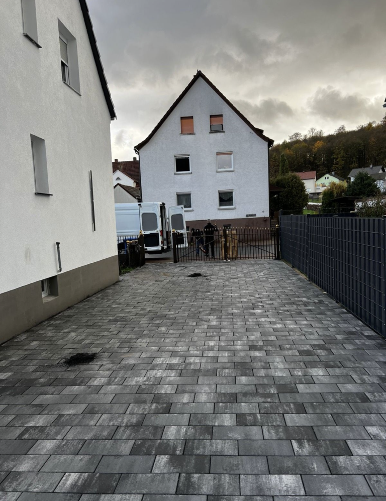 Blick auf einen gepflasterten Weg zwischen weißen Häusern, mit grauem Himmel.