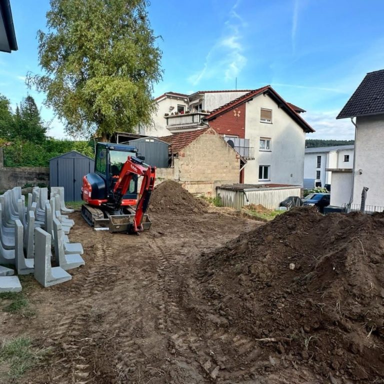 Baustelle mit Erdbewegungsmaschinen und Bauzäunen in einem Wohngebiet.